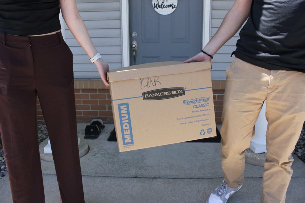 Two people holding a moving box