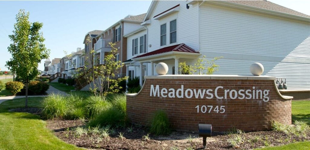 Meadows Crossing sign with townhomes in background and nice landscaping