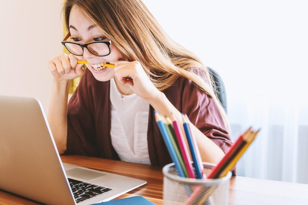 Student biting pencil looking at screen